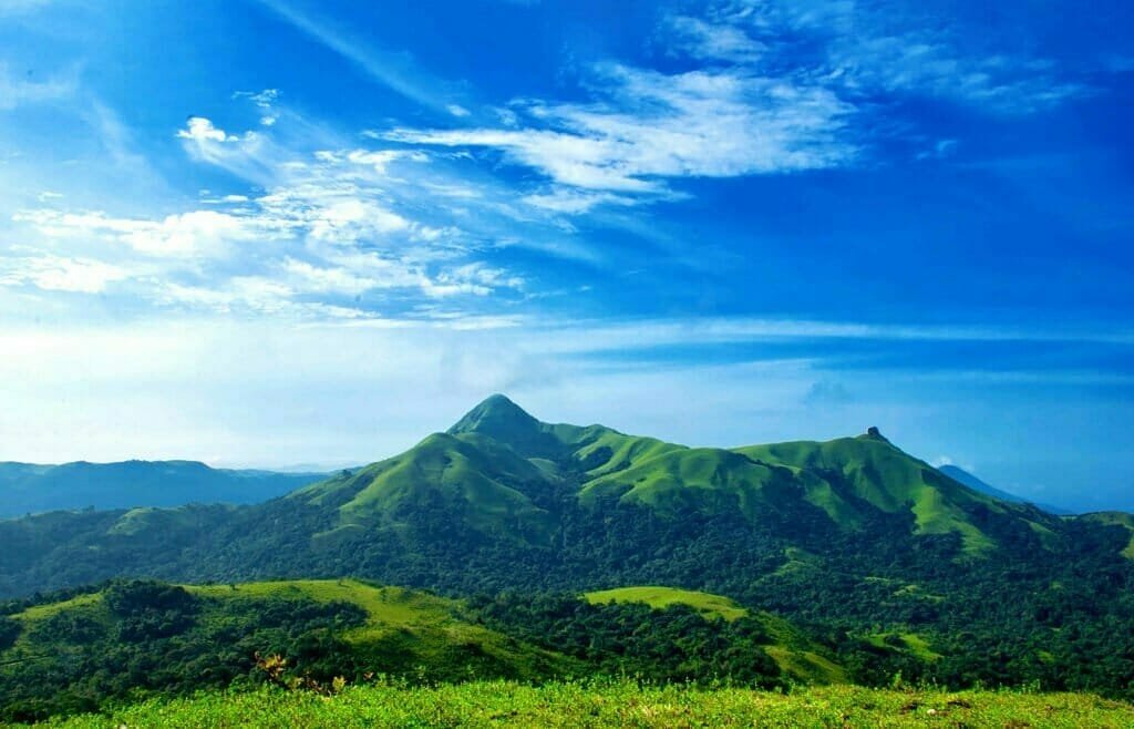 A panoramic view of mist-covered Western Ghats mountains and lush green forests.