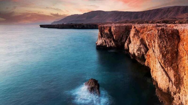 A tranquil stretch of Tiwi Beach, where azure waters meet rugged coastline.